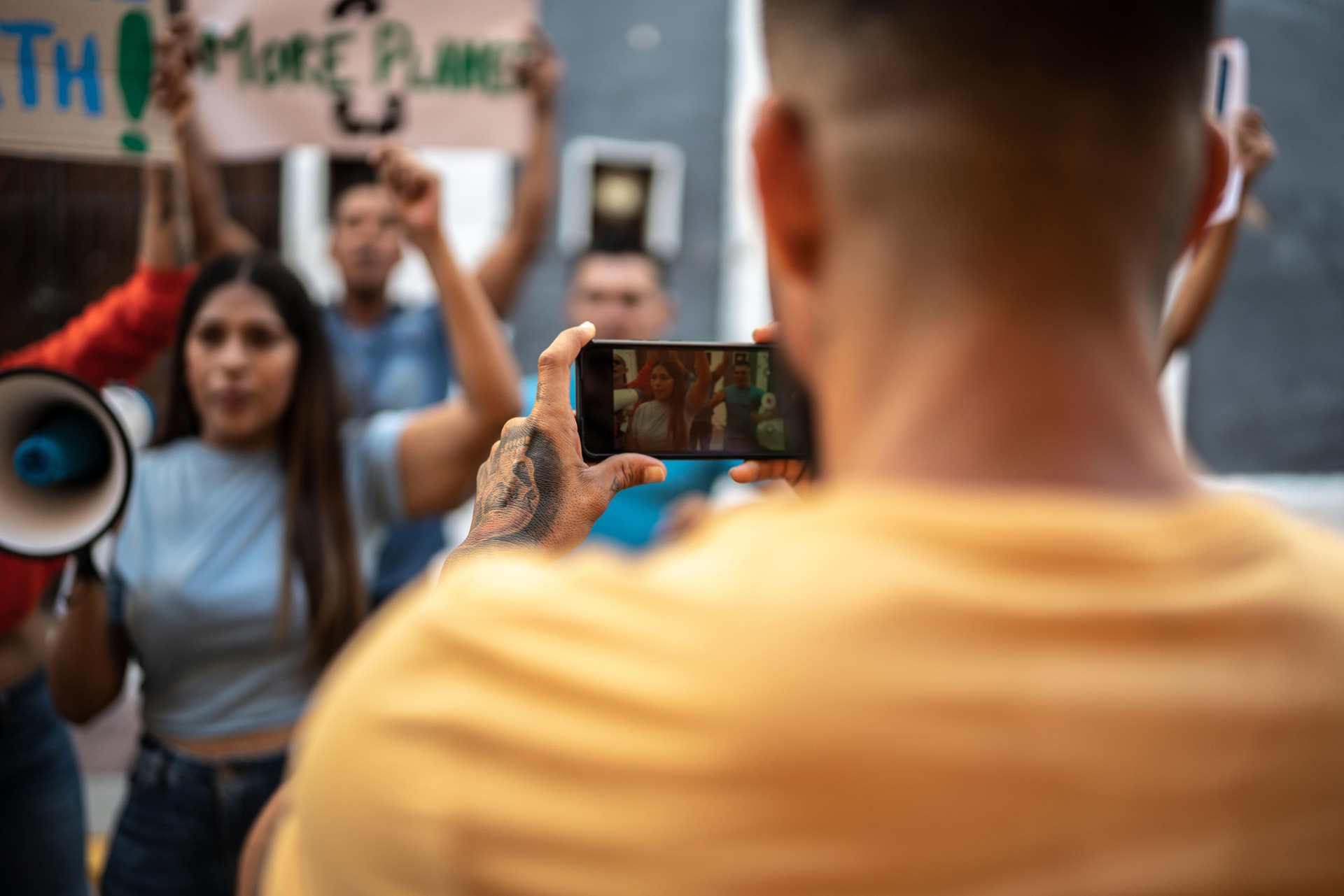 Person recording a protest on mobile phone outdoors
